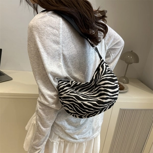 Minimalist zebra print half-moon crossbody bag with wide shoulder strap worn by model