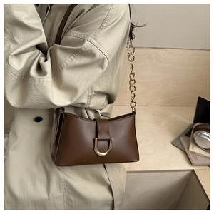 Détail du sac sous le bras en cuir marron foncé avec boucle en D dorée et chaîne