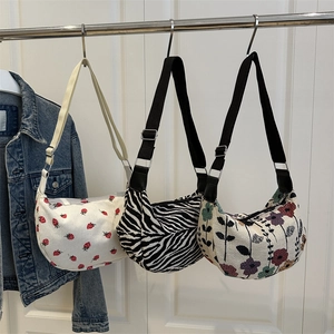 Three half-moon shoulder bags in strawberry, zebra, and floral patterns with straps
