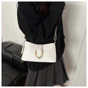 Détail du sac baguette blanc cassé avec boucle dorée en U et bandoulière en chaîne chic