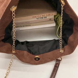 Detail view of large brown tote interior holding a laptop, books, and umbrella