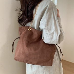 Detail of vintage brown tote bag with gold chain strap and drawstring side accents