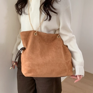 Detail of caramel suede bucket bag featuring drawstring closure and gold chain strap