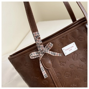 Detail of dark brown tote bag with embossed Braed Cat logo and checkered silk ribbon