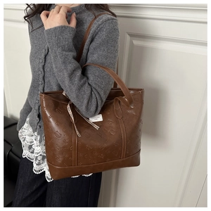 Close-up of brown PU tote bag with Braid Cat embossing and decorative plaid ribbon