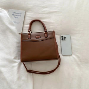 Close-up of brown leather handbag texture with adjustable shoulder strap and handles