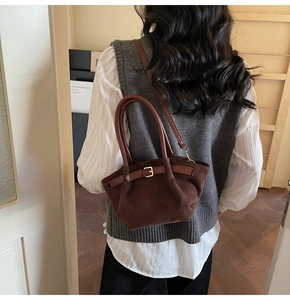 Detail view of the brown suede crossbody bag with vintage bronze buckle and shoulder strap