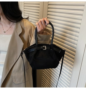 French style black suede bucket bag with leather strap shown in an elegant lifestyle setting