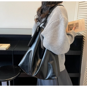 Detail view of large black leather tote bag showing smooth texture and spacious shoulder design
