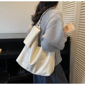 Detail of soft off-white faux leather tote bag with stylish mini pouch charm on shoulder strap