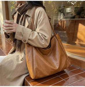 Gros plan détaillé d'un grand sac cabas en similicuir marron porté avec un trench-coat d'automne