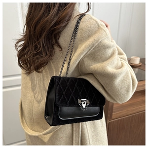 Detail of black quilted velvet crossbody bag with elegant silver chain on wool coat
