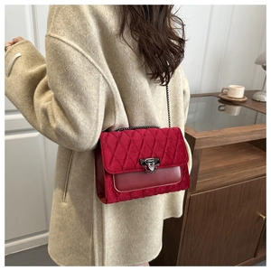 Close-up of red velvet chain bag with diamond stitching on beige wool coat