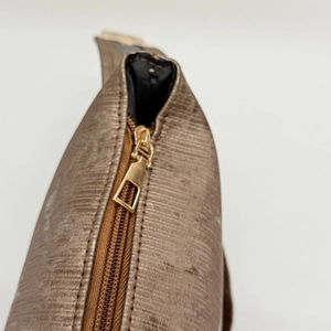 Dettaglio della cerniera dorata e trama a righe della borsa a tracolla bronzo