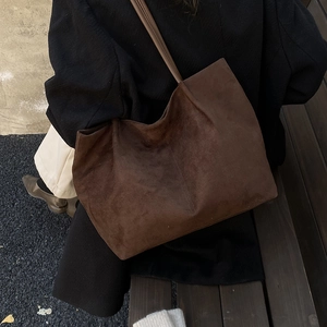 Minimalist large brown faux suede tote bag with slim shoulder straps in outdoor setting