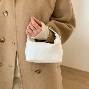 Dettaglio mini borsa a mezzaluna bianca con trama verticale e finiture dorate
