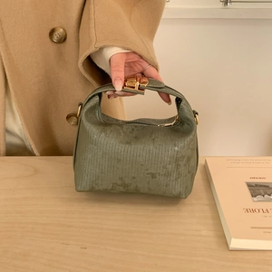 Dettaglio della borsa verde scuro con goffratura verticale e chiusura a scatto dorata