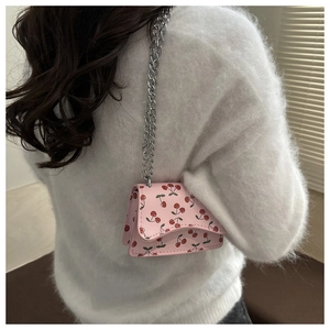 Detail der kleinen rosa Umhängetasche mit Kirschprint und Silberkette an einem Model