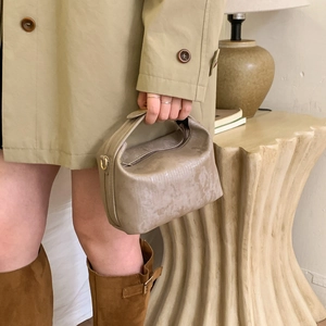 Dettaglio della borsa taupe con anello in metallo dorato e chiusura a zip rifinita