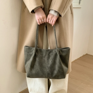Detail of a large dark grey matte leather tote bag with vertical stitching for women