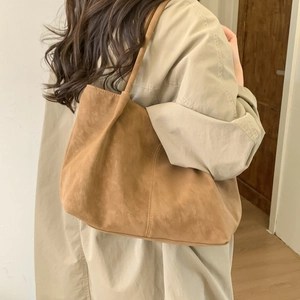 Detailed view of camel suede tote bag showing texture and stitching on shoulder strap