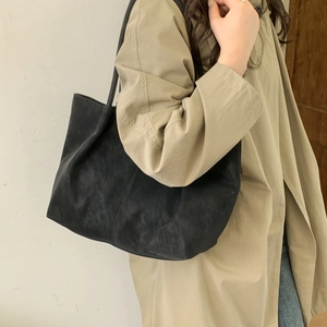 Minimalist large black tote bag in soft suede-textured fabric shown on a model