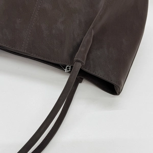 Detailed close-up of dark brown leather tote bag showing fine stitching and metal zipper