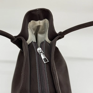Macro view of silver zipper detail and light lining on dark coffee tote bag