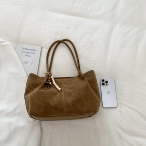 Brown faux suede tote bag with wooden bead charm on white linen background