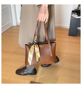 Detailed view of brown leather tote bag with elegant silk scarf wrap on handle