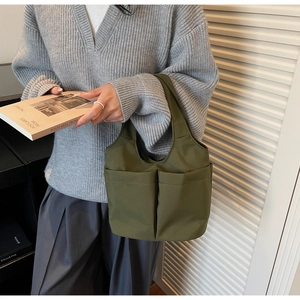 Detail of olive green nylon bucket bag with dual front pockets on casual knit outfit