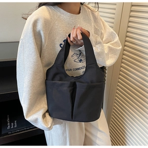 Practical black nylon bucket tote bag featuring front dual pockets shown on a model