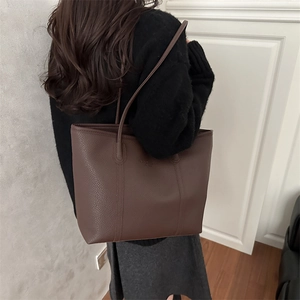 Borsa tote marrone scuro in pelle martellata con lunghe tracolle indossata da modella