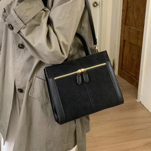 Detail einer schwarzen Umhängetasche im Retro-Look mit goldenen Doppel-Reißverschlüssen