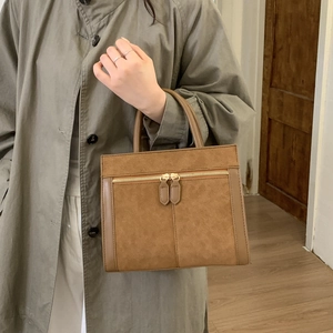 Detailansicht der braunen matten Handtasche mit funktionellen goldenen Reißverschlüssen