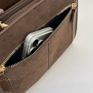 Detail einer braunen Wildlederhandtasche mit Seitentasche für ein Smartphone