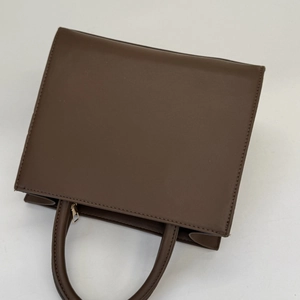 Detail der dunkelbraunen matten Ledertasche mit Akkordeon-Seitenfalten und Goldreißverschluss