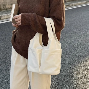 Minimalist beige large capacity tote bag with front pockets and wide shoulder straps