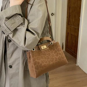 Detail of leopard print crossbody bag with gold twist lock and brown leather strap
