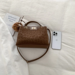 Detail of leopard print handbag with gold twist lock and brown plush charm accessory