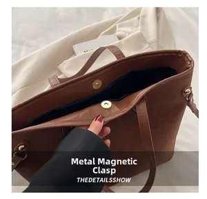 Close-up of golden magnetic snap closure on brown pebbled leather tote bag