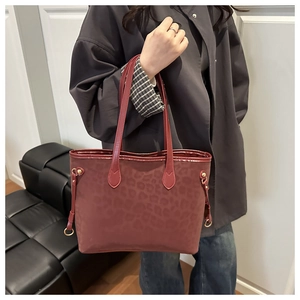 Detail of burgundy leopard print tote bag featuring side drawstrings and gold hardware