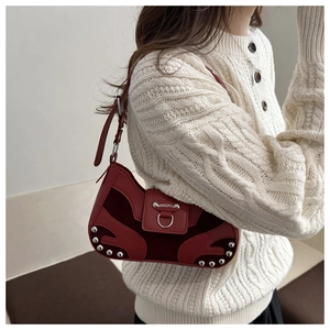 Detail view of red velvet and leather underarm bag with silver rivet studs and hardware