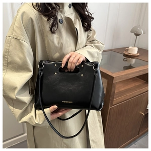 Detailed view of black glossy leather handbag with gold studs and Fashion Bags text