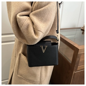 Dettaglio borsa in pelle nera a grana con logo V dorato e tracolla sottile