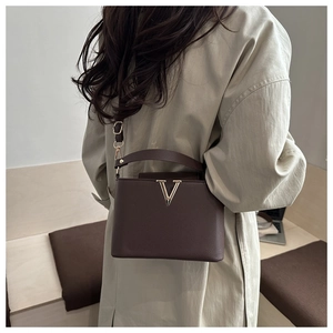 Dettaglio della borsa in pelle marrone scuro con logo V dorato e tracolla regolabile