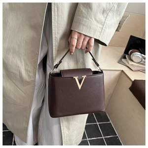 Dettaglio della borsa in pelle marrone scuro con chiusura metallica dorata a forma di V
