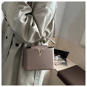 Dettaglio della borsa in pelle taupe con logo V dorato e accessori in metallo