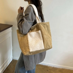 Winter camel suede tote bag with sherpa trim and front pocket shown on shoulder