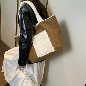 Brown leather tote bag with white faux fur pocket and straps worn by a model